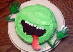 a cake with green frosting and two hands sticking out of it's mouth