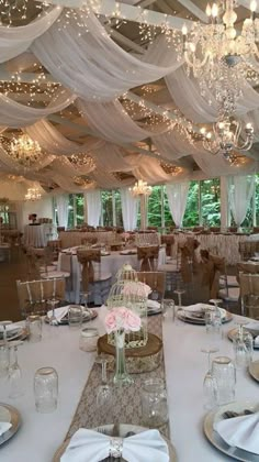 a banquet hall with tables and chairs covered in white draping, chandeliers and flowers