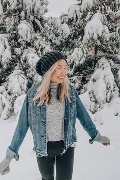 a woman standing in the snow with her arms out and smiling at the camera,