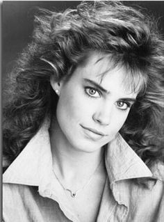 an old black and white photo of a woman with long curly hair, wearing a button up shirt