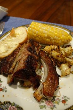 a plate with meat, potatoes and corn on the cob