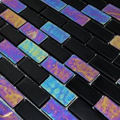 a black and purple mosaic tile wall with multicolored tiles in the center, on top of each other