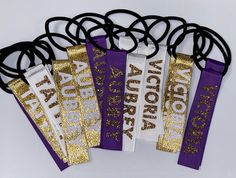 four purple and gold ribbon clips with the words aurora on them in white, black, and gold