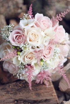 a bridal bouquet sitting on top of a pile of wood next to some rocks