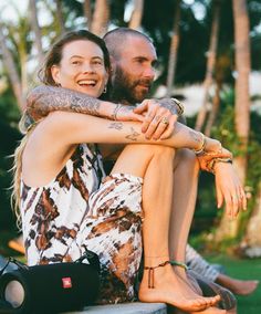 a man and woman sitting next to each other with their arms wrapped around each other