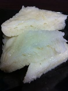 a piece of food that is on top of a black surface with water droplets all over it