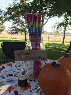 two pumpkins sitting on top of a table next to a jar filled with strawberries