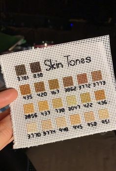 someone is holding up a cross stitch sample