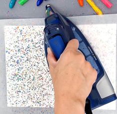 a person is using an electric iron on a surface with colored crayons around it