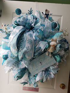 a blue and white christmas wreath hanging on a door with a name tag attached to it