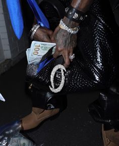 a person holding a black purse with money in it's pocket and wearing bracelets