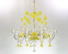 a chandelier with yellow flowers hanging from it's sides and glass pieces on the bottom