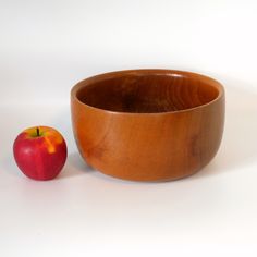 an apple sitting next to a wooden bowl