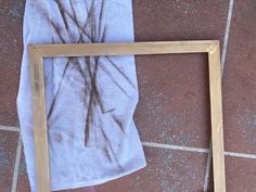 a white towel is laying on the ground next to a wooden frame with a tree drawn on it