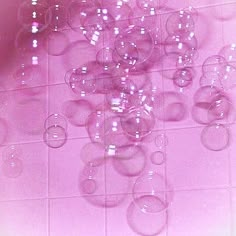 a bunch of wine glasses sitting on top of a white tiled floor next to a pink wall