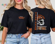 two women wearing black shirts with orange and white football helmets on them, one has her hands in her pockets