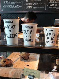 three coffee cups sitting on top of a counter next to doughnuts and muffins