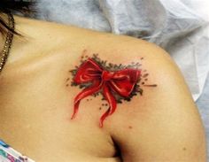 a woman with a red bow tattoo on her shoulder