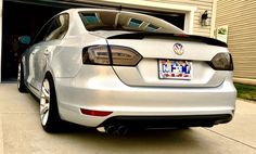 a white car parked in front of a garage with the license plate on it's side