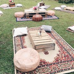 an outdoor seating area is set up in the grass with pillows and blankets on it