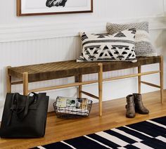 a wooden bench sitting next to a black and white rug on top of a hard wood floor