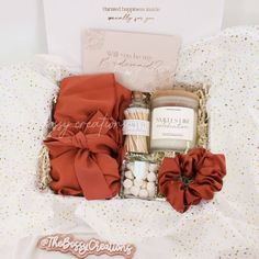 an open gift box containing candles, cookies and marshmallows on a bed