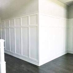 an empty room with white paneling and wood floors