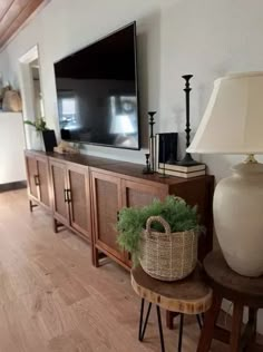 a large flat screen tv sitting on top of a wooden cabinet next to a lamp