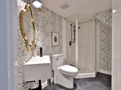 a white toilet sitting in a bathroom next to a walk in shower and tiled walls