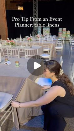 a woman is setting up tables at an event with chairs and table linens on them