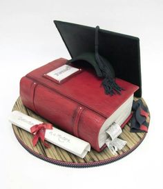 a cake made to look like a book with a graduation cap on top and diploma