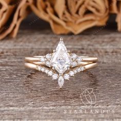 an engagement ring with a pear shaped diamond surrounded by smaller diamonds on a wooden surface