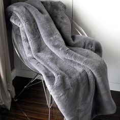 a gray blanket sitting on top of a chair next to a white window sill