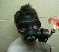 a man wearing a gas mask holding a lighter