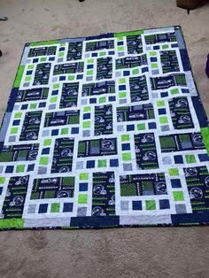 a green and blue quilt sitting on top of a floor next to a pair of purple shoes