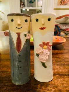 two vases with faces painted on them sitting on a table