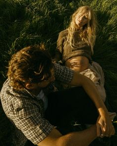 a man sitting next to a woman in the grass