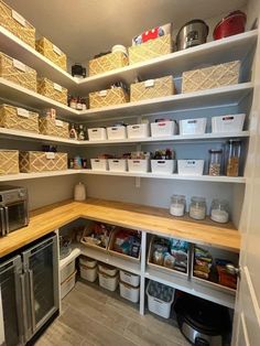 an organized pantry with lots of items in baskets and bins on the shelves above