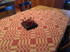 a candle is sitting on top of a table with red and white quilted fabric