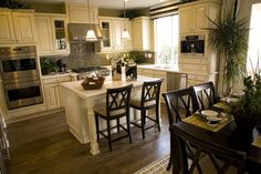 a kitchen filled with lots of counter top space and wooden flooring next to a dining room table