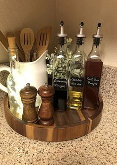 an assortment of cooking utensils and bottles on a wooden tray in a kitchen