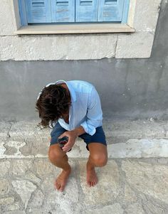 a woman kneeling down on the ground with her hands in her pockets