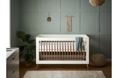 a baby crib in the corner of a room with green walls and wooden flooring