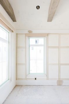 an empty room with white walls and windows