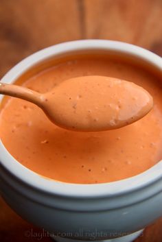 a spoon full of tomato sauce in a white bowl with a wooden spoon sticking out of it