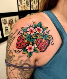 a woman with a tattoo on her shoulder has strawberrys and flowers in the center