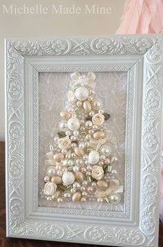 a christmas tree made out of shells and pearls is displayed in a frame on a table