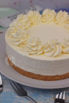 a cake with white frosting sitting on top of a plate next to silverware