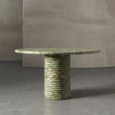 a round table made out of coils on top of concrete flooring in front of a wall