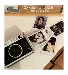 a polaroid camera sitting on top of a table next to pictures and a cork board